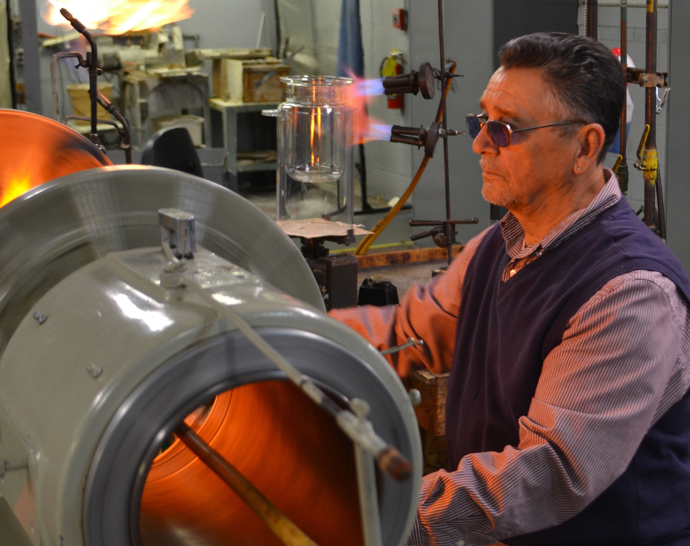 custom glass blowing Labware glassware consumables A man with goggles on blowing glass.